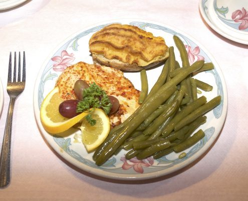 Plated meal with protein, potato, and green beans on floral china