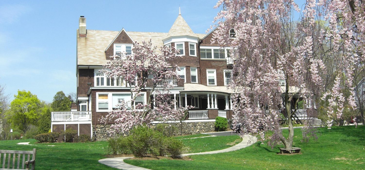 Victoria Home exterior in spring with flowering trees and wraparound porch